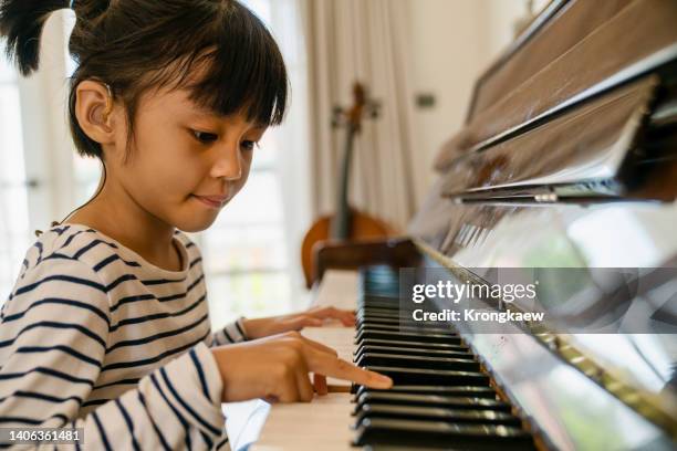 girl wearing a hearing aid plays piano at home. - practicing piano stock pictures, royalty-free photos & images