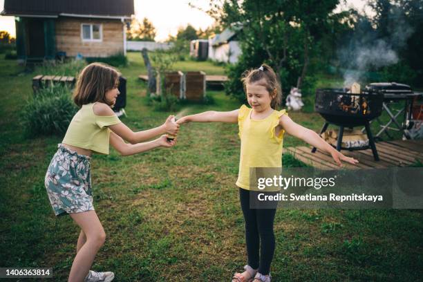 girl spraying her sister from a spray can with mosquito spray - mosquito bite stock-fotos und bilder