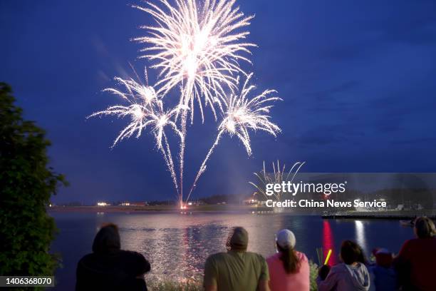 People watch as fireworks explode during Canada Day celebrations for its 155th birthday on July 1, 2022 in North Rustico, Prince Edward Island,...