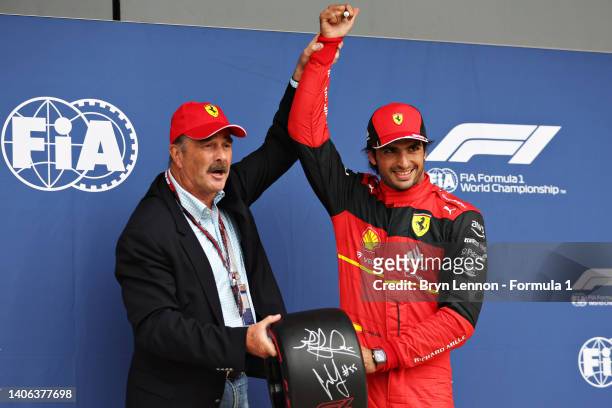 Pole position qualifier Carlos Sainz of Spain and Ferrari is presented with the Pirelli Pole Position trophy by Nigel Mansell in parc ferme during...