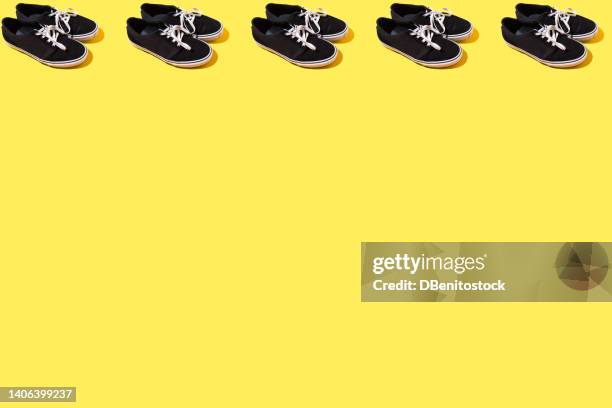 pattern of black and white canvas and rubber surfer and skater sneakers with white laces, on top, on a yellow background. concept of skateboarding, surfing, fashion, sneakers, modern, retro. - trainer cutout stockfoto's en -beelden