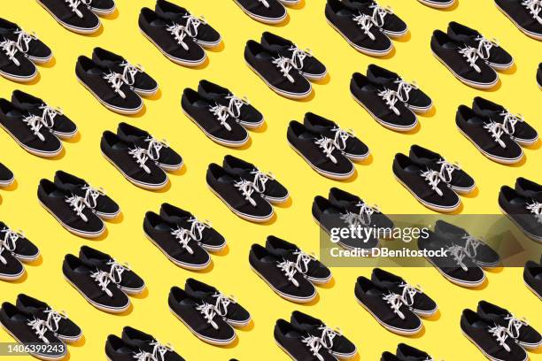 pattern of black and white canvas and rubber surfer and skater sneakers with white laces, on a yellow background. concept of skateboarding, surfing, fashion, sneakers, modern and retro. - skateboard shop stock pictures, royalty-free photos & images