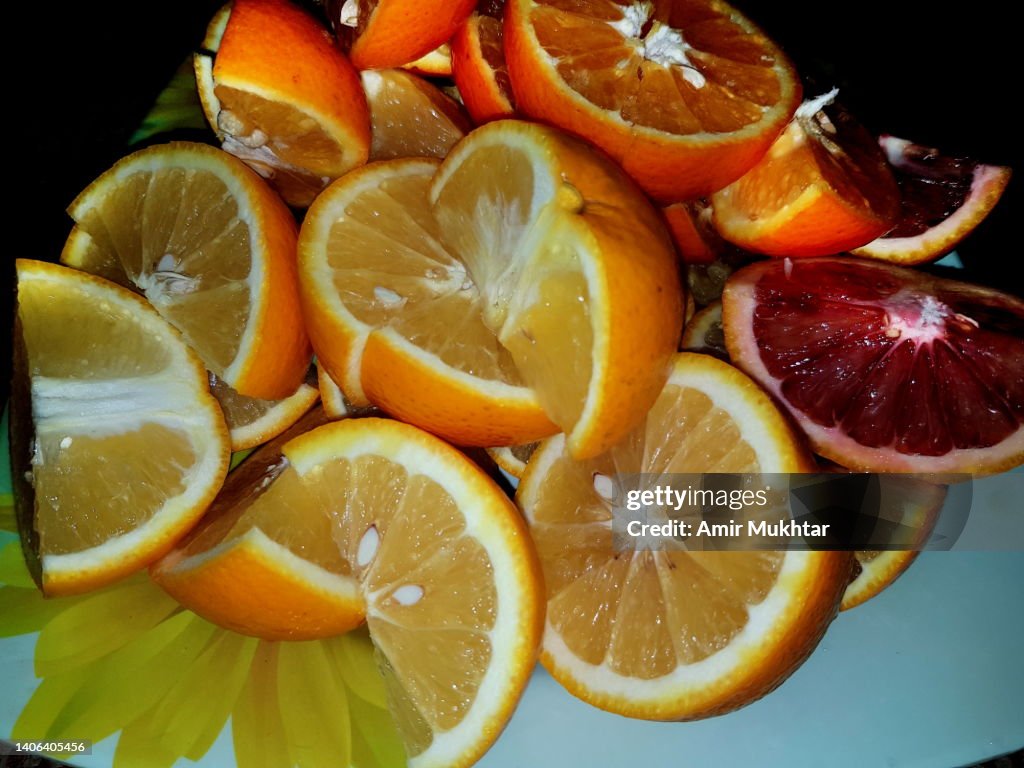 Fresh ripe blood oranges cut in slices or pieces in a plate.