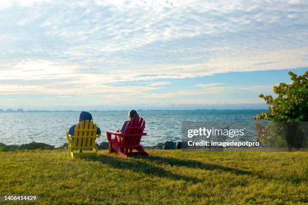 two happy women sitting by seaside and watching view - sarasota stock pictures, royalty-free photos & images