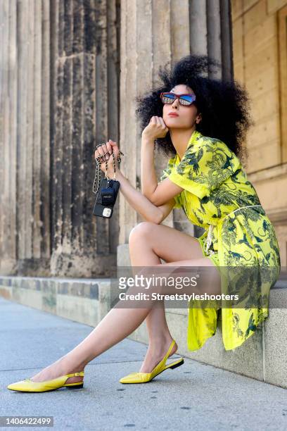 Model and artist Zoe Helali wearing a yellow top, shorts and jacket with floral and animal print by Miss Goodlife, a black and gold phone case with...
