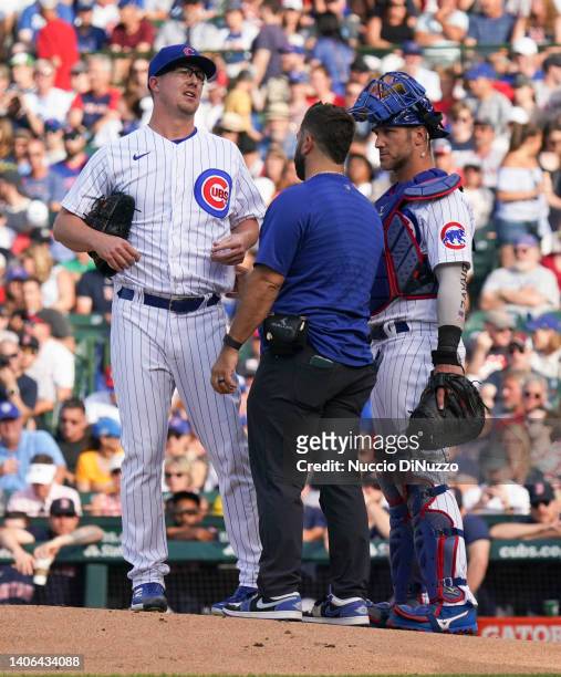 Alec Mills of the Chicago Cubs is checked by athletic trainer Nick Frangella beore leaving the game due to lower back pain during the first inning of...