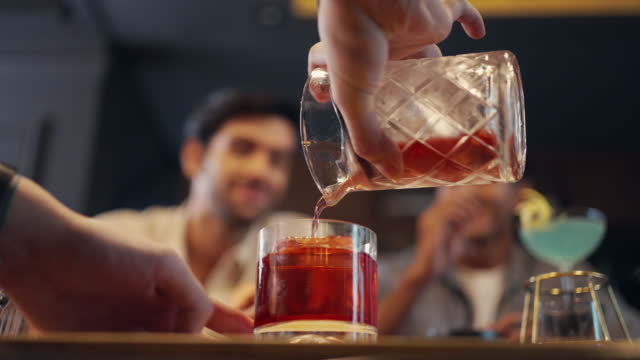 4K Male bartender preparing cocktail drink serving to customer on bar counter at luxury bar.