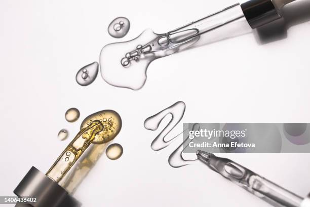 many glass pipettes spilling drops of different moisturizing lotions on luxury silver background. polyglutamic acid is new hyaluronic acid. macro photography - oil macro stock pictures, royalty-free photos & images