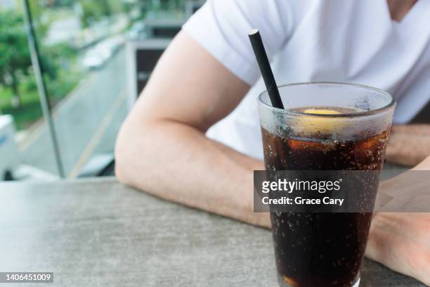 man drinks beverage with paper straw at restaurant - cola stock-fotos und bilder