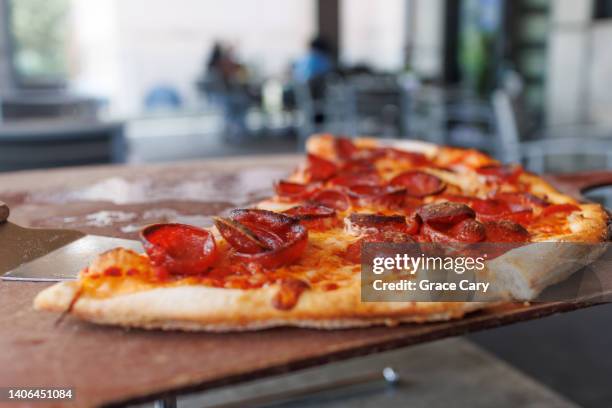 leftover slices of pepperoni pizza at restaurant - american pizza stock-fotos und bilder