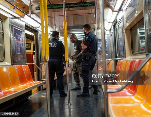 New York Police Department officers order a subway traveler to leave the car after he was seen with an open beer can July 2, 2022 in New York City....