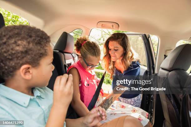 mother buckling daughter's seat belt in the back of the car - sicherheitsgurt teil eines fahrzeugs stock-fotos und bilder