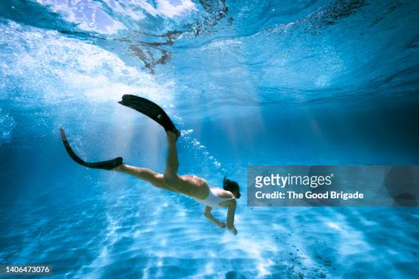 wide shot of woman snorkeling in ocean - zwemvliezen stockfoto's en -beelden