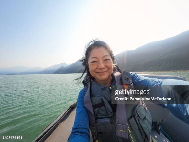 60+ senior asian woman riding in fishing boat taking selfie - bc commercial fishing boats stock pictures, royalty-free photos & images