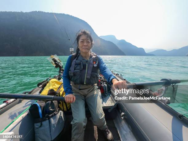 60+ senior woman using oars on boat while lake fishing - bc commercial fishing boats stock pictures, royalty-free photos & images