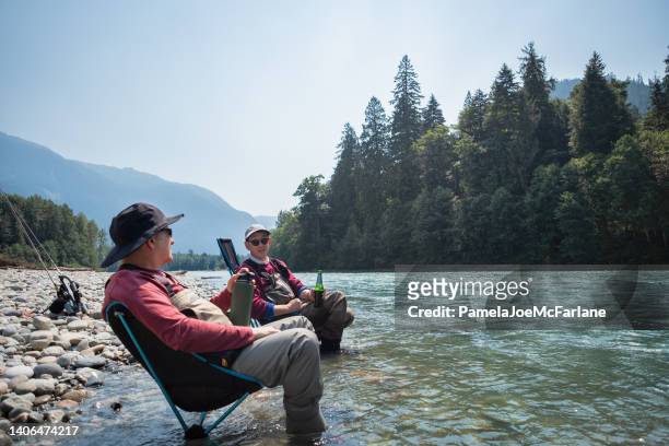 60+ multiracial senior friends taking drink break from freshwater fishing - canadian senior men stock pictures, royalty-free photos & images