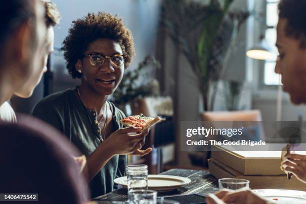 young male and female friends enjoying pizza at home - male student wearing glasses with friends stock-fotos und bilder