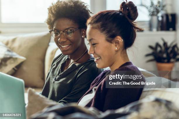smiling female friends using laptop at home - streaming service stock pictures, royalty-free photos & images