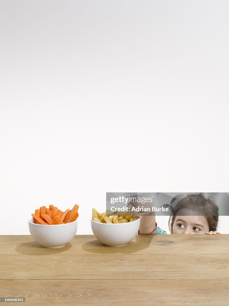 Small girl pinching chips from a bowl