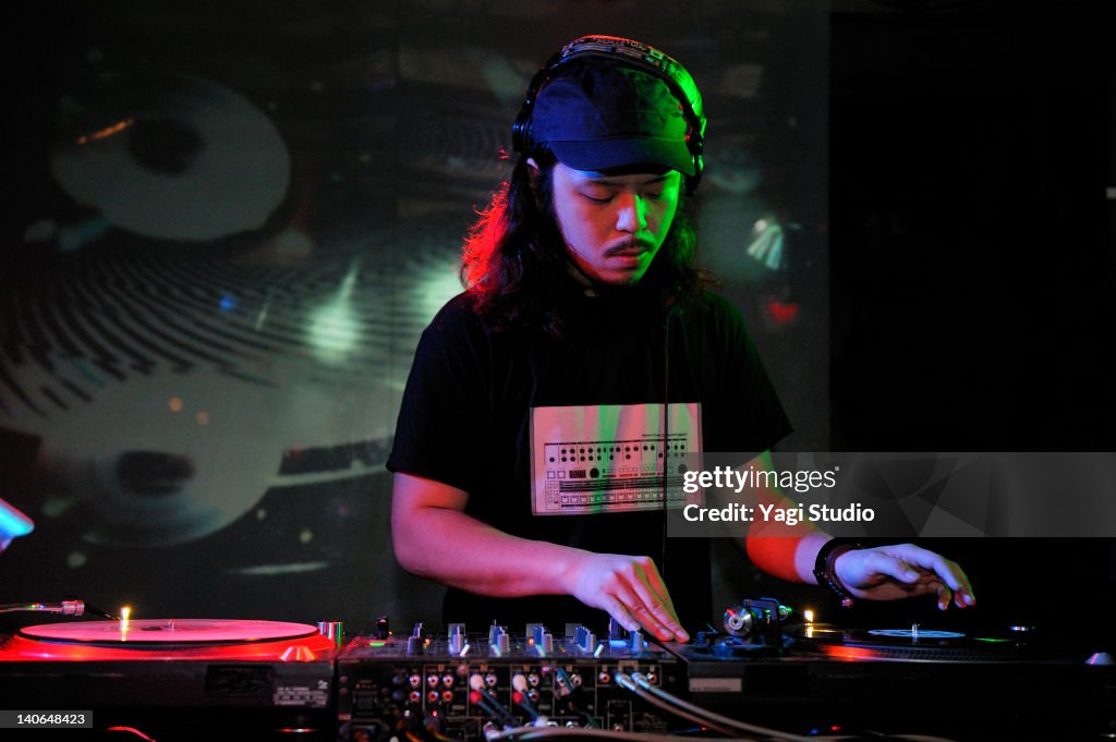 Young male DJ at record decks in nightclub,Japan