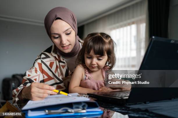 middle eastern mother working from home with kid - hemmavarande förälder bildbanksfoton och bilder