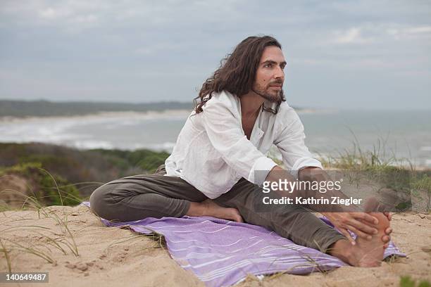 man practicing yoga in the dunes - soles pose stockfoto's en -beelden