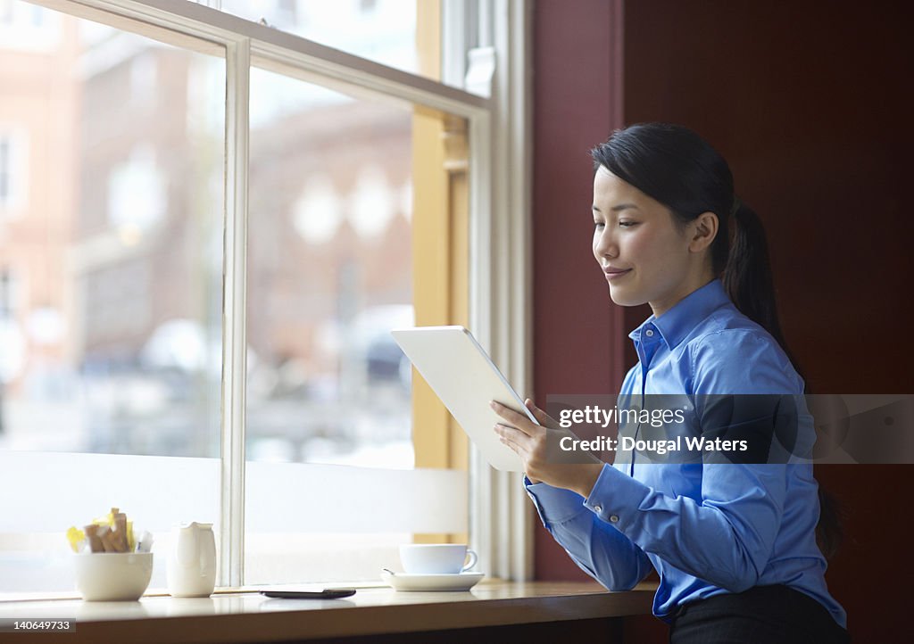 Asian business woman using digital tablet in cafe.