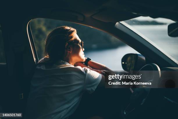 young woman enjoying the car ride at sunset. cute young woman hanging from a car. - roadtrip imagens e fotografias de stock