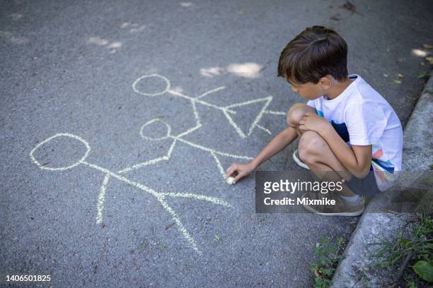 boy drawing his family on the asphalt - family chalk drawing stock pictures, royalty-free photos & images