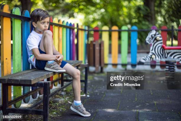 kid sitting on a bench and feeling lonely - child abuse stock pictures, royalty-free photos & images