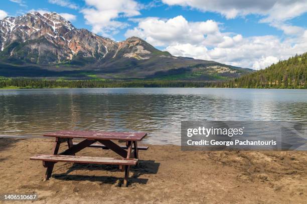 wooden pin-nic table on the beach of a lake - garden table stock-fotos und bilder