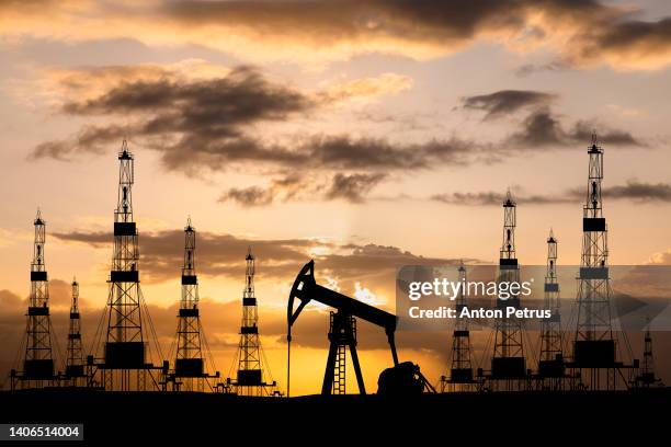 oil field with rigs and pumps at sunset. world oil industry - oil stockfoto's en -beelden