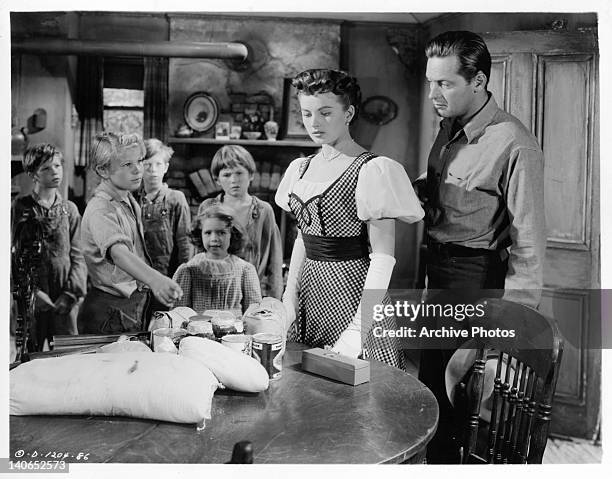 Children show Coleen Gray and William Holden items sitting on table in a scene from the film 'Father Is A Bachelor', 1950.
