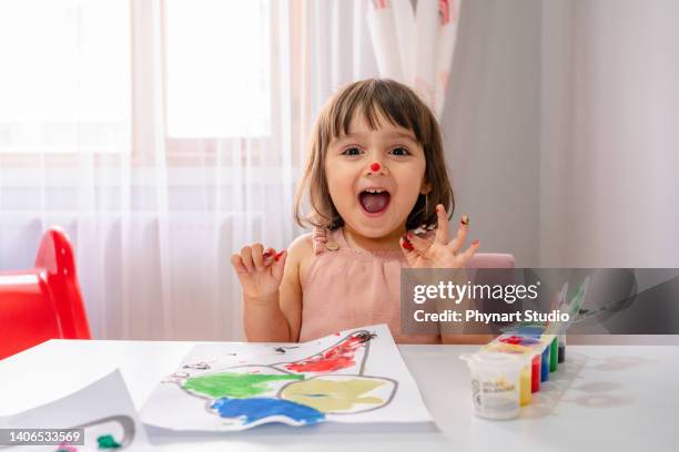 cheerful little child having fun doing finger painting - cute arab girls stock pictures, royalty-free photos & images
