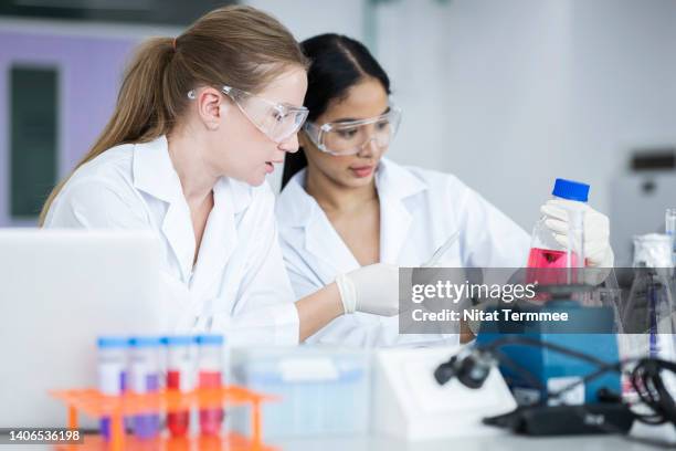 pharmaceutical and life sciences research. female scientists or research is working in the medical laboratory while decision on chemical test data from experiment together. - microbiologist fotografías e imágenes de stock