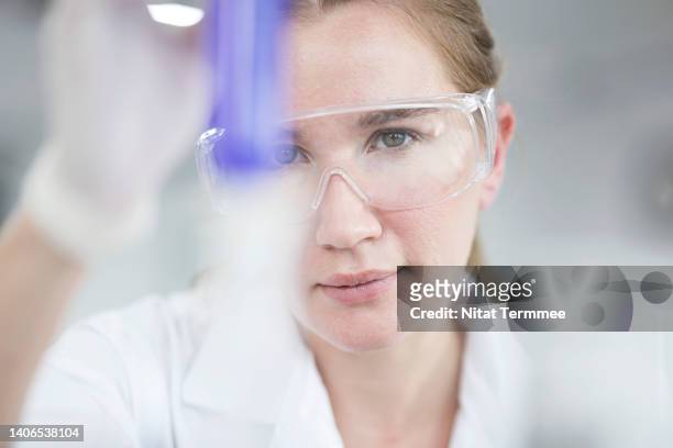 pharmaceutical, biotech research and development. female chemist analyzing on chemical sample through a test tube at laboratory. - genomics stock-fotos und bilder