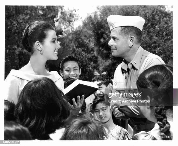 Gia Scala smiles her thanks to Glenn Ford in front of school children in a scene from the film 'Don't Go Near The Water', 1957.