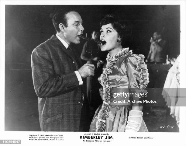 Jim Reeves eating sausage with unidentified woman in a scene from the film 'Kimberley Jim', 1965.