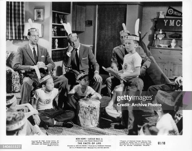 Indian feather wearing Bob Hope, two men, and children wathc child speaking before the group in a scene from the film 'The Facts Of Life', 1960.