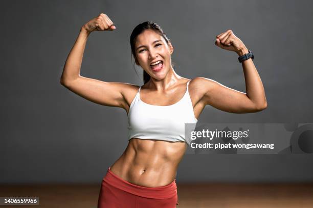 asian woman exercising showing her muscles in the gym, fitness and wellness concept. - asian female bodybuilder stock-fotos und bilder