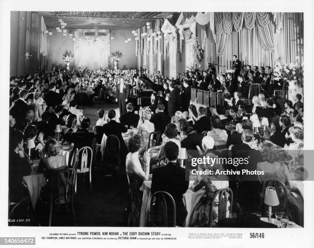 Tyrone Power as pianist Eddy Duchin stands by piano dressed in a tuxedo as audience applauds him in a scene from the film 'The Eddy Duchin Story',...