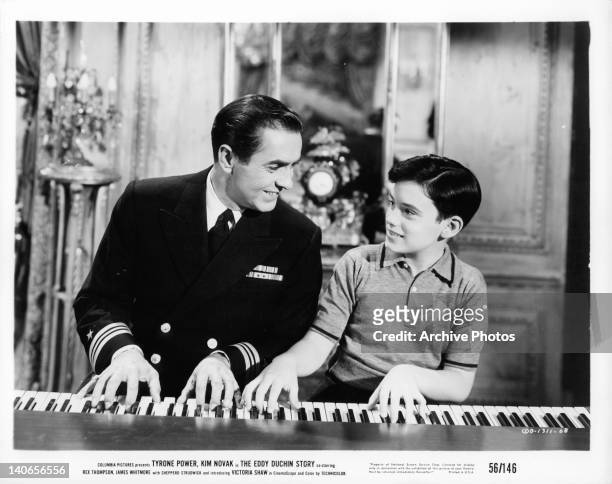 Tyrone Power plays piano with young boy in a scene from the film 'The Eddy Duchin Story', 1956.