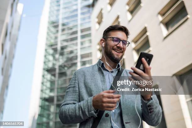 video call on smart phone - young man listening to music on smart phone outdoors stockfoto's en -beelden