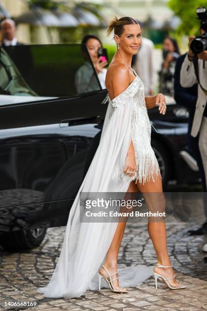Guest wears silver and diamonds earrings, a white with embroidered mirror shoulder-pff long train, a silver fringed V-neck / short dress, silver and...