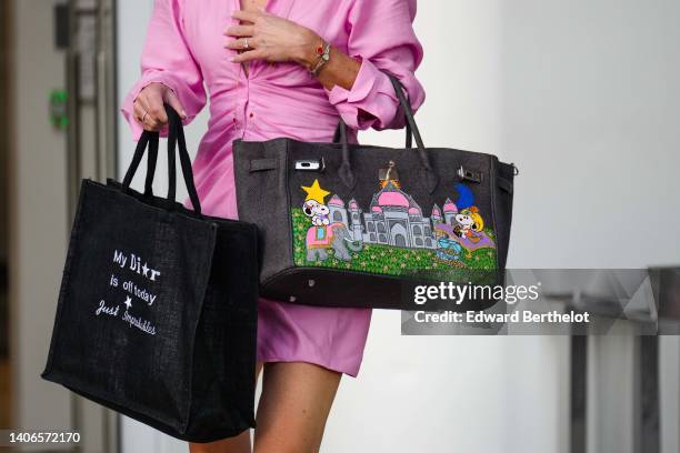 Guest wears a pale pink shirt dress, a black linen handbag, a dark gray denim with embroidered multicolored Snoopy print pattern large Birkin handbag...