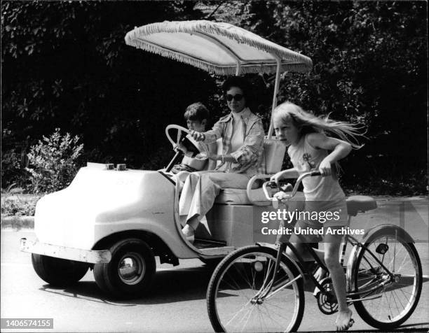 Das Bild zeigt Rosalynn Carter, die Ehefrau des US-Präsidenten Jimmy Carter, in einem Golfwagen mit einem Kind. Neben dem Auto fährt ihre Tochter Amy...