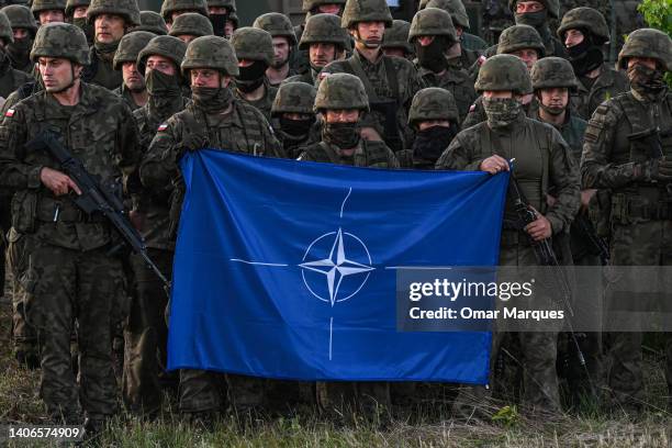 Polish soldiers hold a NATO flag during a family photo after a training demonstration with the NATO multinational battle group eFPon at the Orzysz...