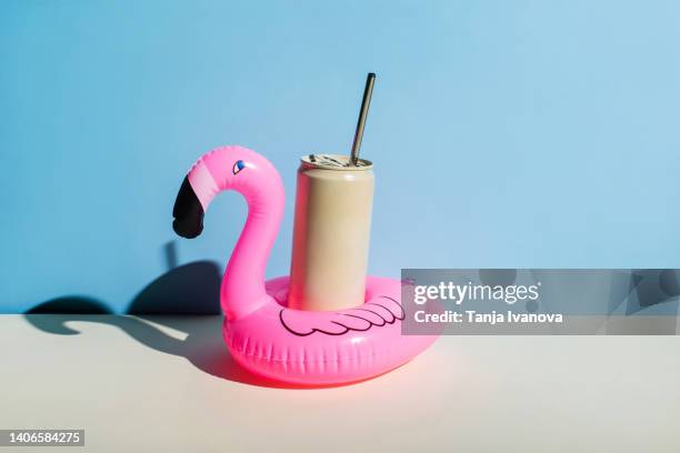 pink inflatable flamingo with a can of cooling drink on a blue background. summer holidays concept. - can beach sun photos et images de collection