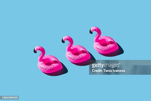 pattern of pink inflatable flamingo on blue background. summer holiday concept. - flamingos stock-fotos und bilder