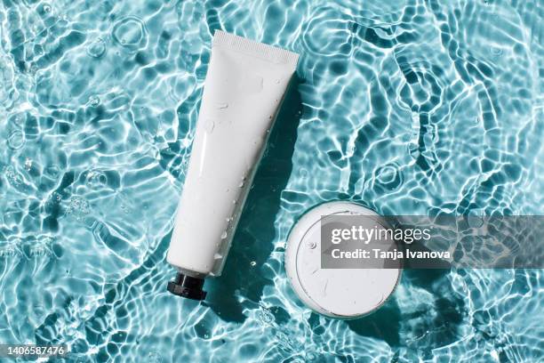 bottles of natural cosmetics with sunscreen against sunburn on the background of blue water with waves. beauty products for body and face care. - cosmetic jar stockfoto's en -beelden